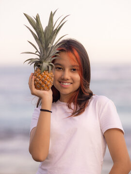 Close up portrait of girl holding pineapple in front of her face. Tropical fruit concept. Smiling face. Lifestyle. Bali.