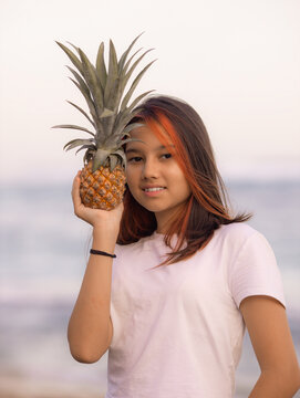 Close up portrait of girl holding pineapple in front of her face. Tropical fruit concept. Smiling face. Lifestyle. Bali.