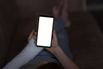 Cropped close-up shot of a boy with a broken arm wrapped in a white plaster cast. Teenager uses phone, white chromakey