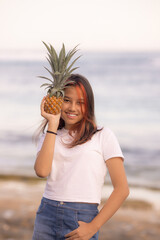 Teenager girl holding pineapple in front of her face. Tropical fruit concept. Smiling face. Lifestyle. Bali island.
