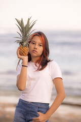 Teenager girl holding pineapple in front of her face. Tropical fruit concept. Summer vacation. Lifestyle. Bali island.