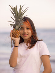 Close up portrait of girl holding pineapple in front of her face. Tropical fruit concept. Smiling face. Lifestyle. Bali.