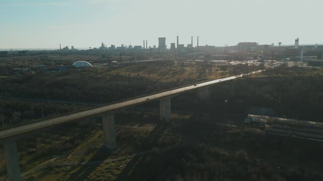 Vehicles Driving At Viaduct Bridge In Galati, Romania. Steel Manufacturing Plant In Background. wide drone shot