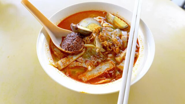 Close up of a bowl of hokkien mee or prawn noodle in prawn-based soup which is popular in Malaysia and Singapore. Toppings include eggs, meat slice and tofu.