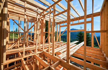 Residential wooden frame building in progress near a forest. Start of new construction of comfortable house. The idea of modern ecological building techniques and contemporary architecture.