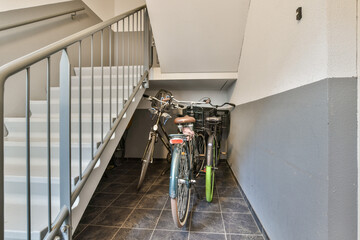 Two bicycles are parked against a wall in a stairwell, showcasing a modern and functional interior...