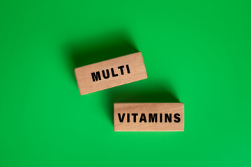 multi vitamins words on wooden blocks isolated on green background