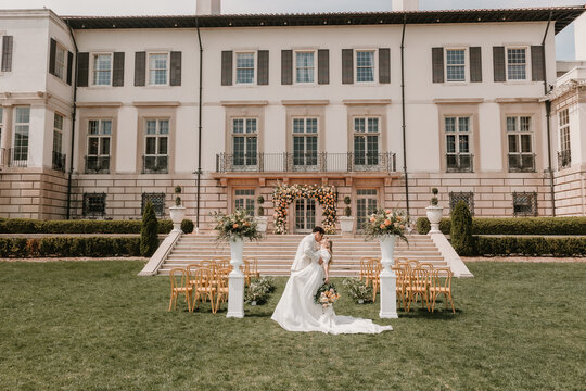 Bride and groom kiss at elegant outdoor wedding in front of a mansion