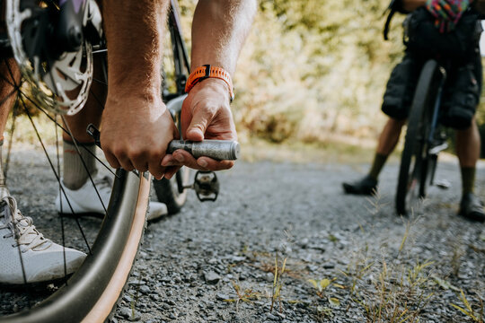 Close up of cyclist pumping air into tire on gravel road