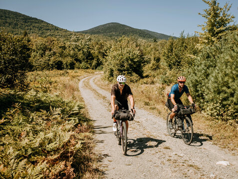 two cyclists bikepack on gravel road deep in Maine woods