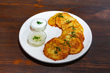 Crispy potato pancakes served with creamy dips on a wooden table
