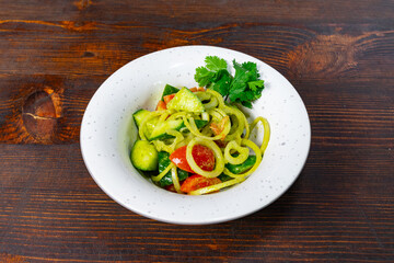 Fresh vegetable salad with spiralized cucumbers on wooden table