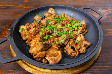 Savory stir-fried meat with green onions on dark wooden table