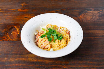 Delicious pasta dish served in a white bowl on wooden table