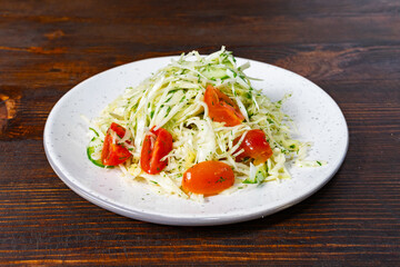 Fresh coleslaw salad with cherry tomatoes on a white plate
