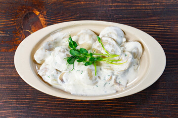 Delicious dumplings served with creamy sauce on a wooden table