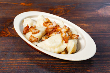 Traditional dumplings with crispy bacon on a rustic table