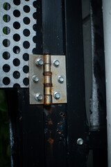 Rusty door hinge, installed to black metal gate, with shallow depth of field