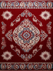 Ornate red carpet with intricate floral and paisley patterns in blue, cream, and white. Symmetrical design with a central medallion, exuding elegance