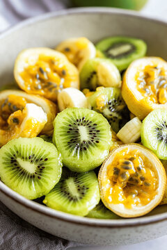 Healthy bowl of banana, passion fruit, and kiwi fruit salad, fresh and colorful