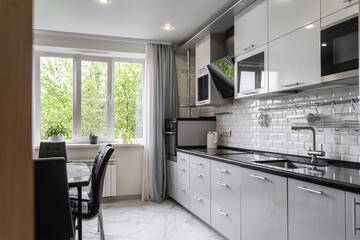 interior of modern apartment. design of built-in kitchen with white cabinets and black countertops....