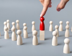 Obraz premium Businessman’s hand pointing at a red wooden figure among white ones on a grey background, symbolizing human resources and selection