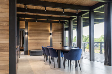 modern large kitchen in country house. kitchen with large wooden table and blue chairs in elite wooden villa. upper and lower cabinets in wooden kitchen. built-in furniture. wooden countertop 