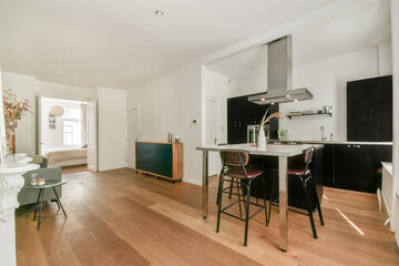 A stylish and airy modern kitchen seamlessly integrated with a living area. The design features light wood flooring and sleek cabinetry for an inviting atmosphere.