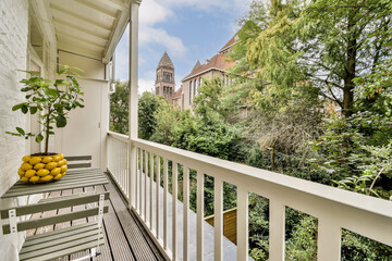 Fototapeta premium A beautiful balcony adorned with plants and lemons, offering a view of vibrant greenery and a stunning historic building in the background.