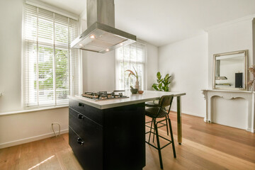 A contemporary kitchen featuring sleek cabinetry, an island with bar stools, and plenty of natural light coming through large windows.