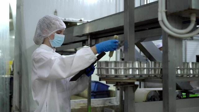 A female quality control supervisor or food technician is checking an automated production system in a ready-to-eat food manufacturing plant.