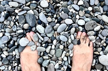 Close up of feet in the pebbles on the beach 