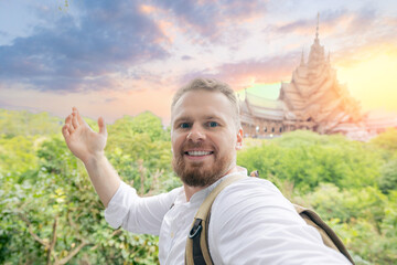 Caucasian male adult taking selfie at truth wooden temple, Pattaya, Thailand sunset
