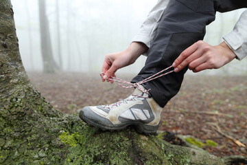 Trekker tying shoelaces of boots in nature