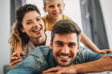 Fototapeta premium Family from three people cheerfully spends fun time at home together. Parents, kid happiness concept