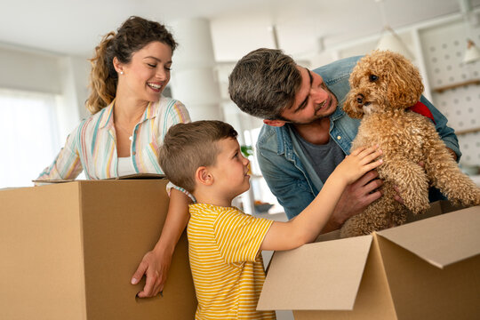 Smiling man and woman enjoy unpacking with child moving to own home. Rent, mortgage concept