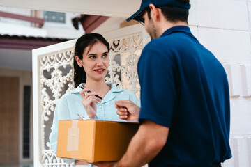 A woman receives a package and scans it to pay the delivery man during rush hour outside her house.