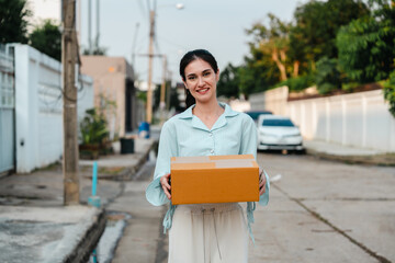 A woman receives a package from a delivery man during rush hour in front of her house.