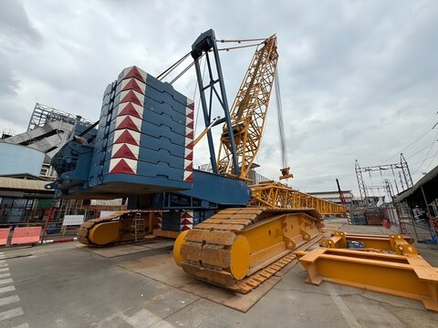 Large crawler crane with massive counterweights in construction and industrial site. Heavy lifting equipment for engineering and installation work.