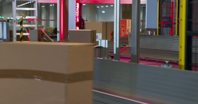 Various Sized Brown Cardboard Packages Move Along a Modern Autonomous Conveyor System in a Large Modern Distribution Facility. Advanced Logistics and Sorting Center Operating at a Retail Warehouse