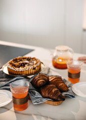 A cozy breakfast setup with croissants, tart, and tea.