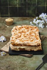 Norwegian dessert, the best cake with meringue, almonds and custard on a black dish on a green  background. Norwegian cuisine.