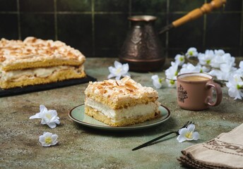 Norwegian dessert, sliced best cake with meringue, almonds and custard on a dessert plate on a green concrete background. Norwegian cuisine.