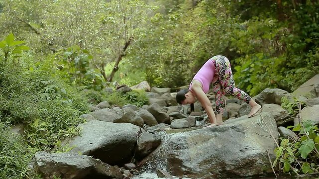 Flexible Woman Doing Standing Split Yoga Pose on Rocks by River