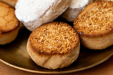 A close-up of traditional Spanish sweets, including polvorones and mantecados with sesame alongside turron