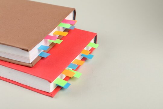 Books with colorful tabs on light gray background, closeup. Space for text