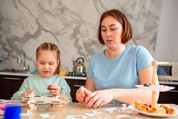 Fototapeta premium Mid shot of Caucasian mother and a little daughter are preparing for the holiday by decorating eggs for the Easter spring