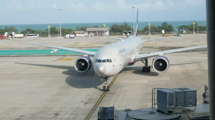 airplane while arriving to the parking area gate of the airport with background of the the sea view.landscape view of airport airside area in summer holiday time