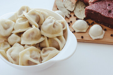 A piece of beef meat and beef dumplings on a kitchen board. A banner with meat products marbled beef peppercorns and bay leaves. High quality photo