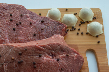 A piece of beef meat and beef dumplings on a kitchen board. A banner with meat products marbled...